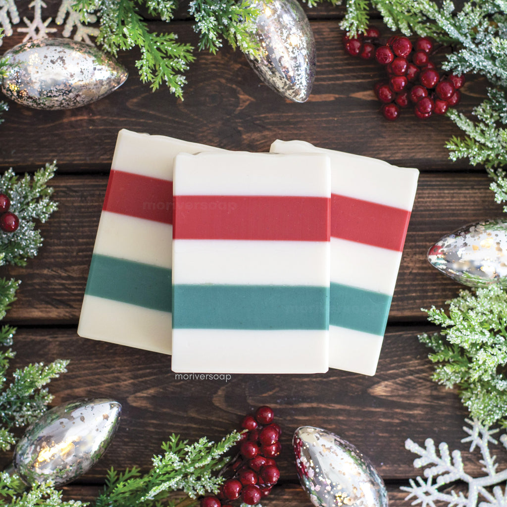 Image of Bayberry Soap with layers of white, red, white, green, and white. A festive holiday background of sparkly evergreen, red berries, and silver metallic christmas lights.