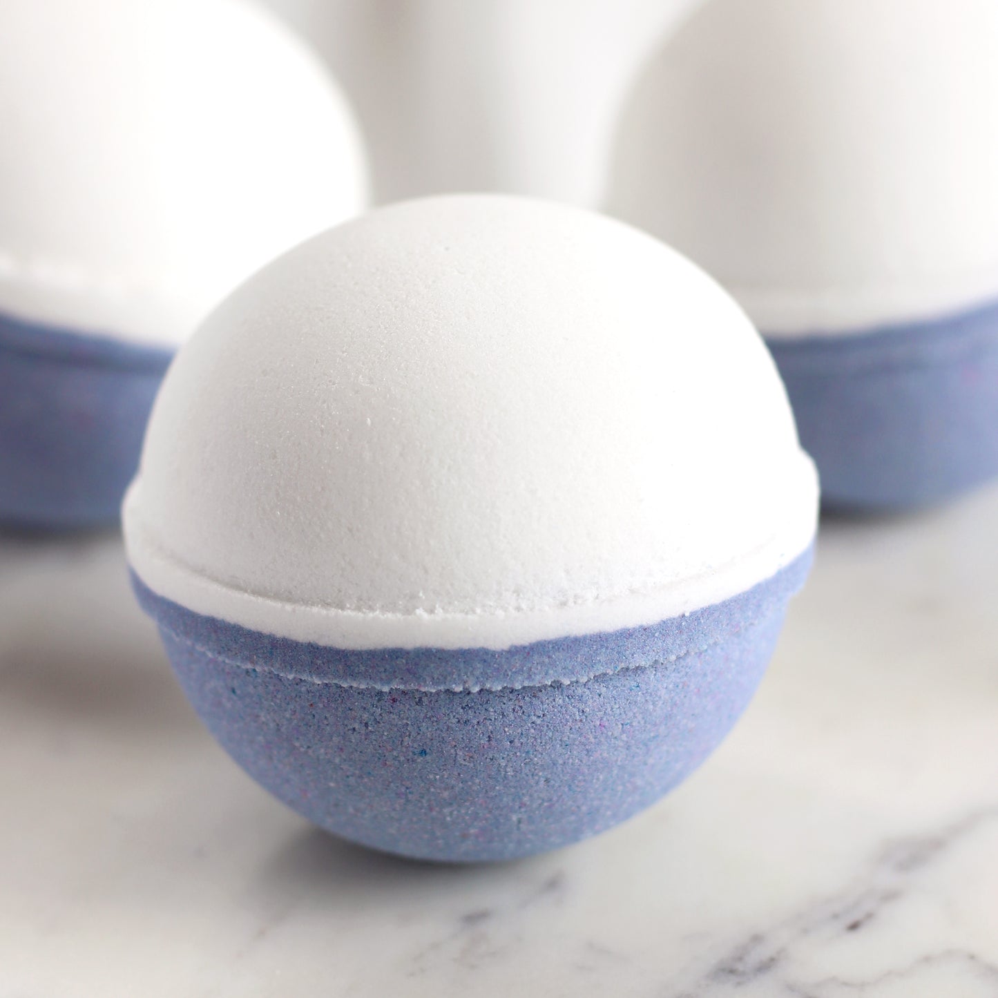 White and blue bath bombs on a marble surface