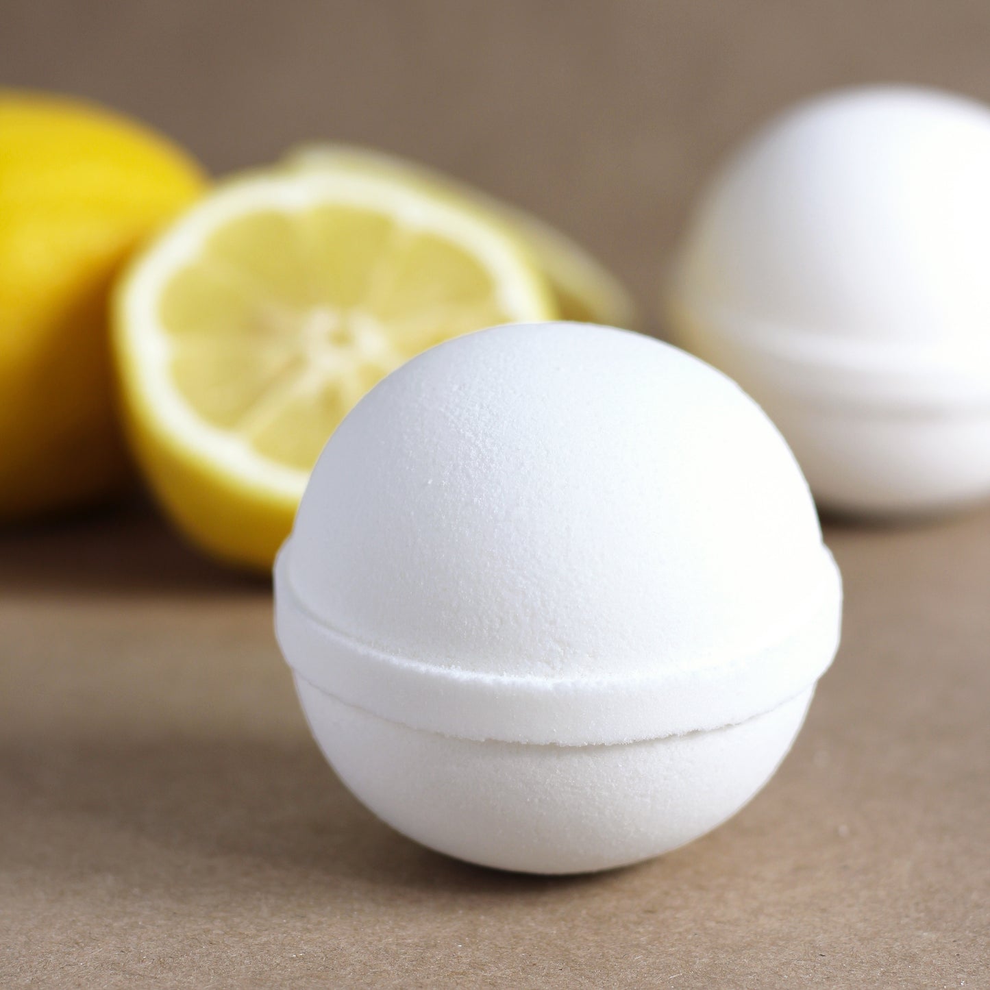 White spherical bath bomb with lemons in the background on a neutral surface