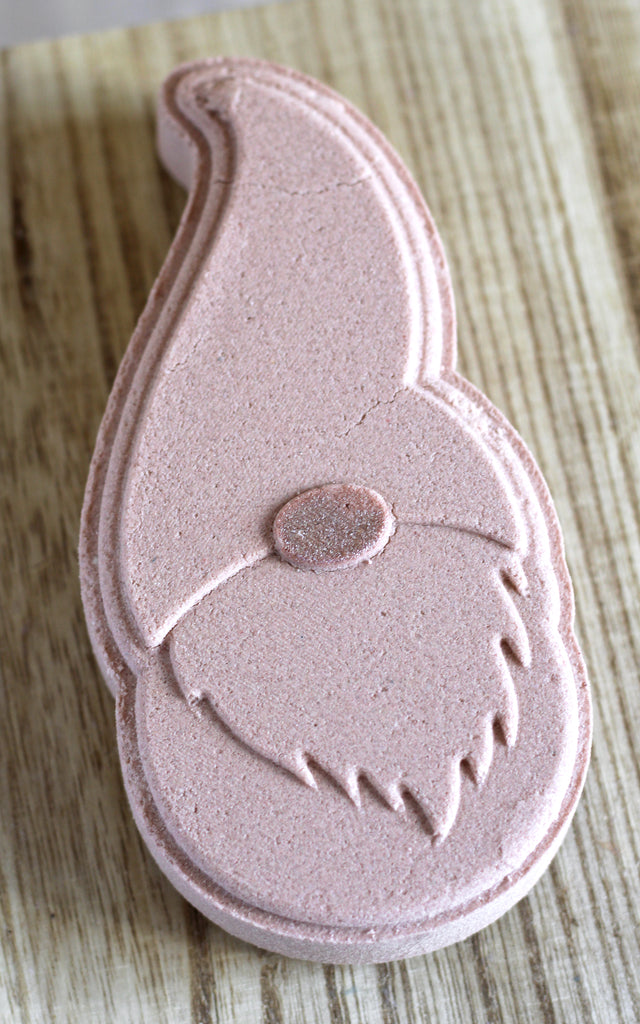 Light brown gnome-shaped bath bomb on a wood surface.
