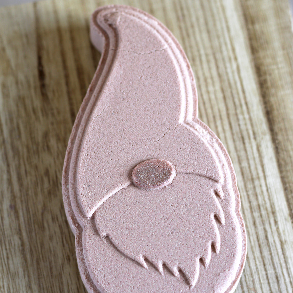Light brown gnome-shaped bath bomb on a wood surface.