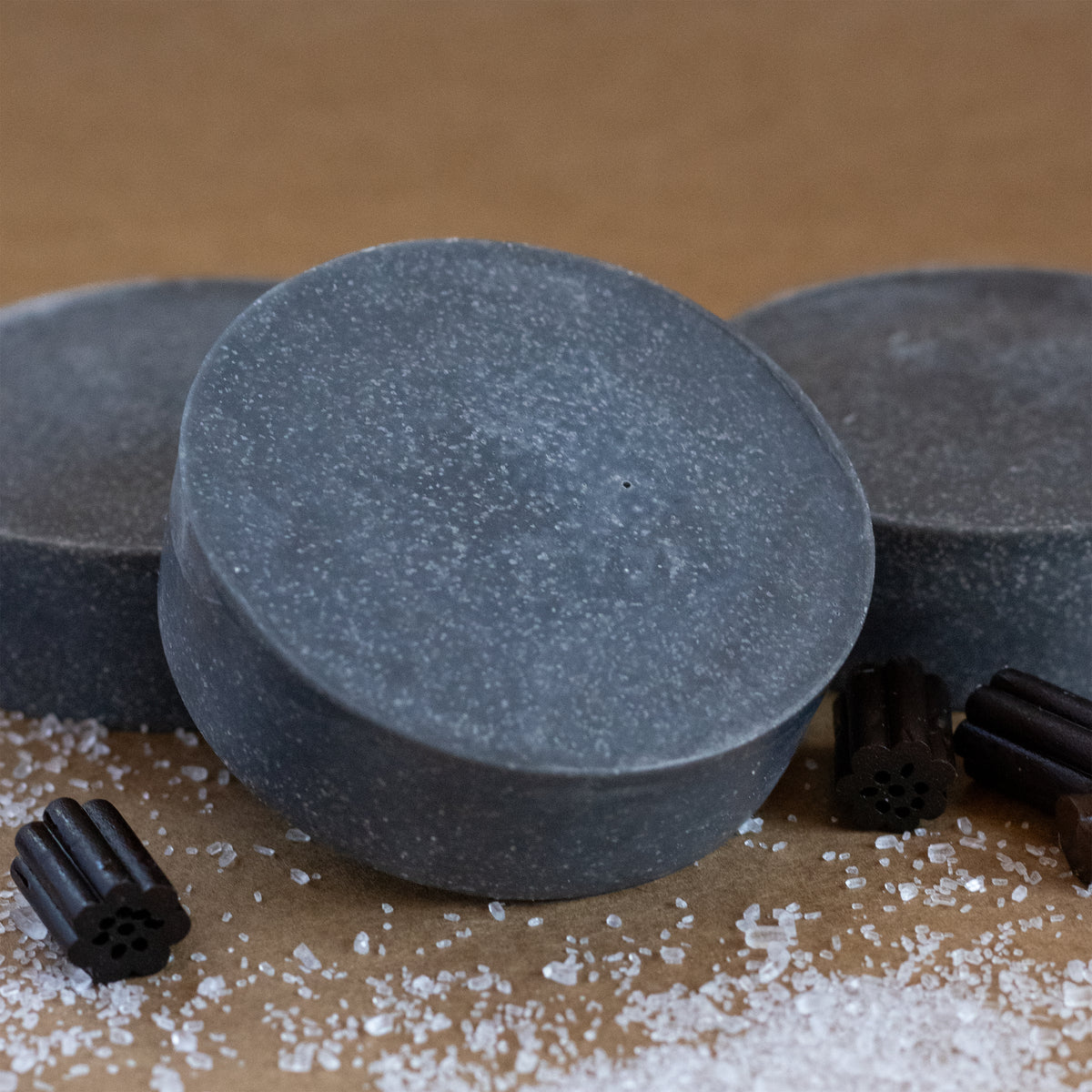 Missouri River Soap Anise Essential Oil Soap featuring deep charcoal-colored bars surrounded by black licorice pieces and scattered salt crystals.