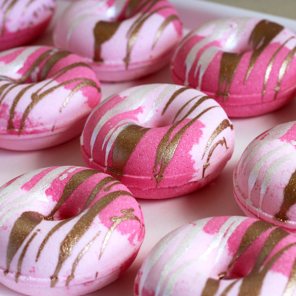 Pink donut-shaped bath bombs with copper and white drizzle 