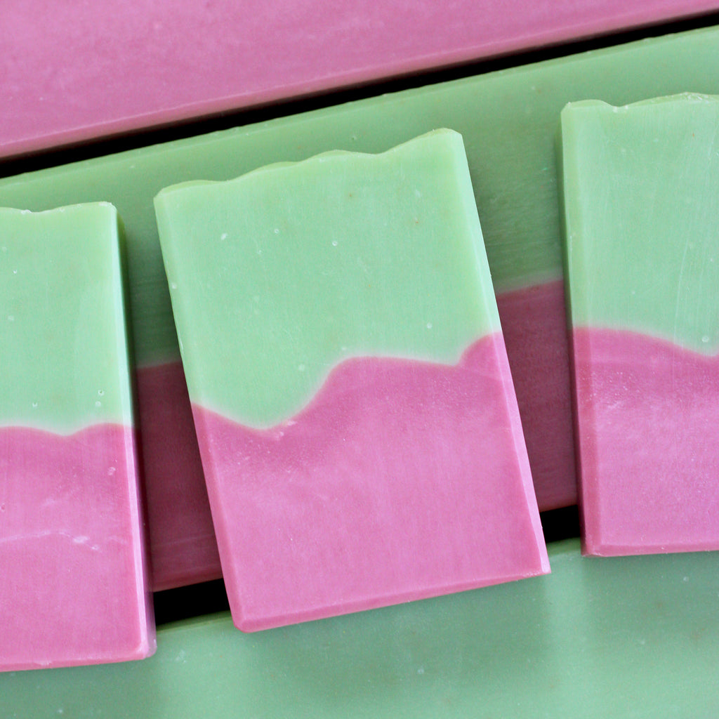 Pink and green soap bars on a green and surface