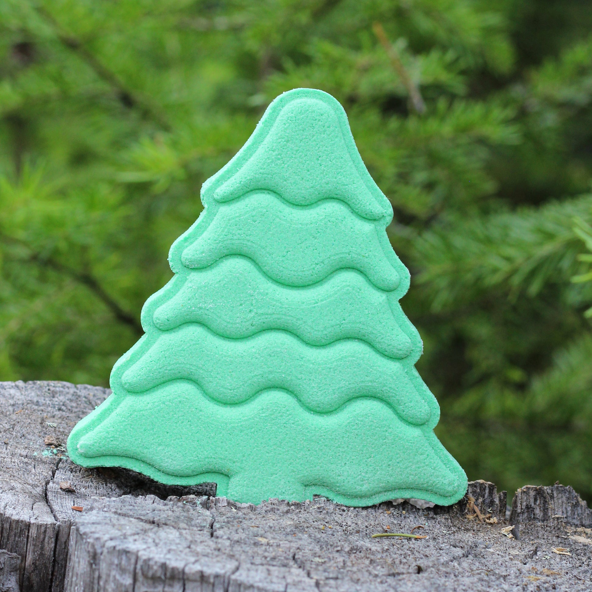 Evergreen tree-shaped bath bomb by Missouri River Soap photographed on a tree stump in the forest