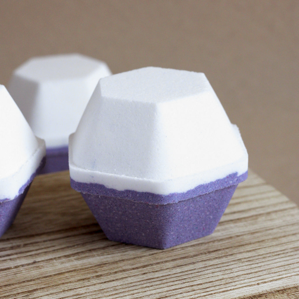 Hexagon bath bombs that are half white and half dark purple