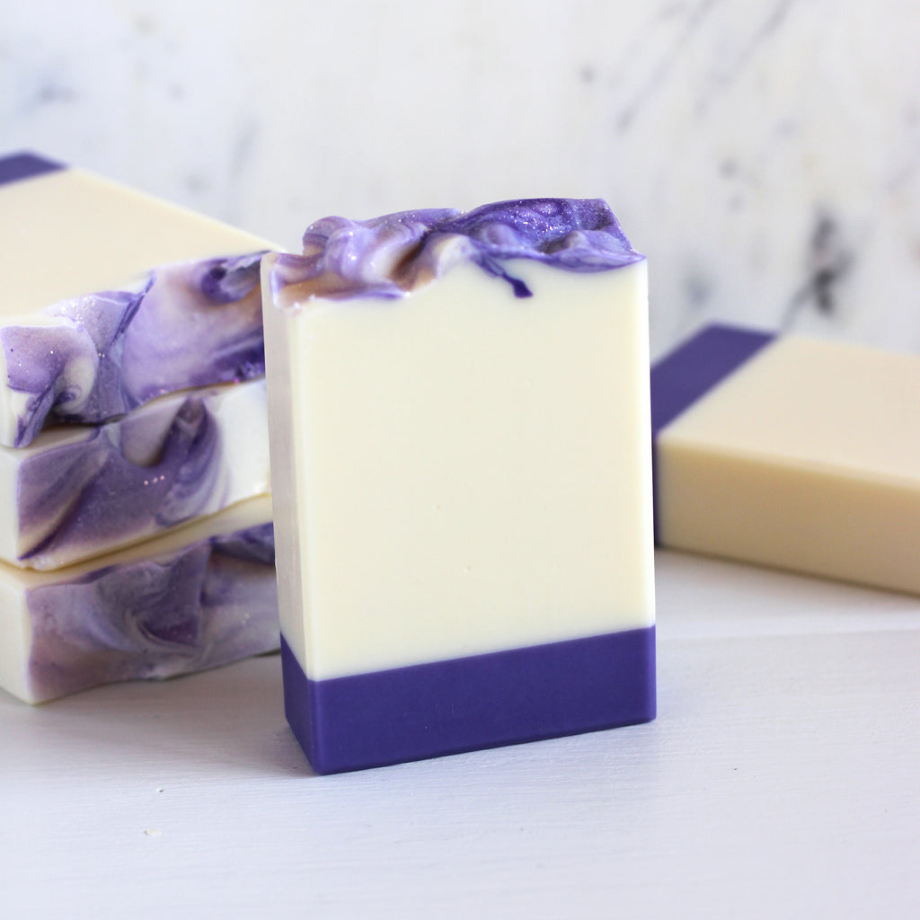 Three bars of soap with purple and white on a marble surface