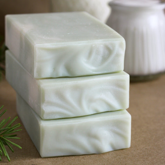 Missouri River Soap Fir Needle Tallow Soap featuring three creamy white handcrafted soap bars stacked on kraft paper with goat milk kefir, sheep's milk yogurt, and a fresh fir sprig in the background.