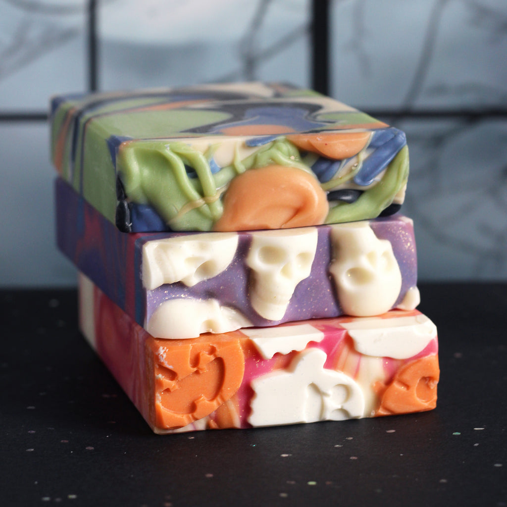 Stack of colorful soap bars with Halloween designs on a black surface.