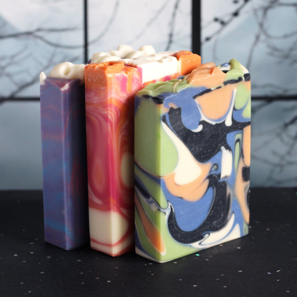 Three halloween themed soap bars on a black surface and a blurry background