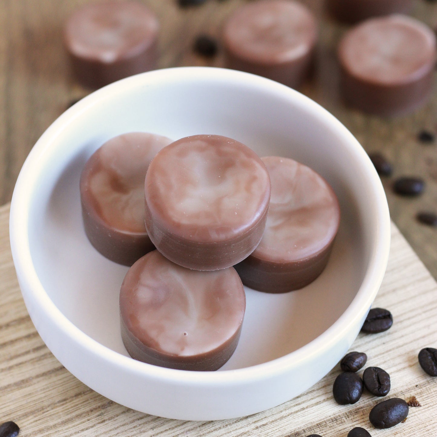 Brown and white swirled disk-shaped wax melts in a bowl on a wooden surface