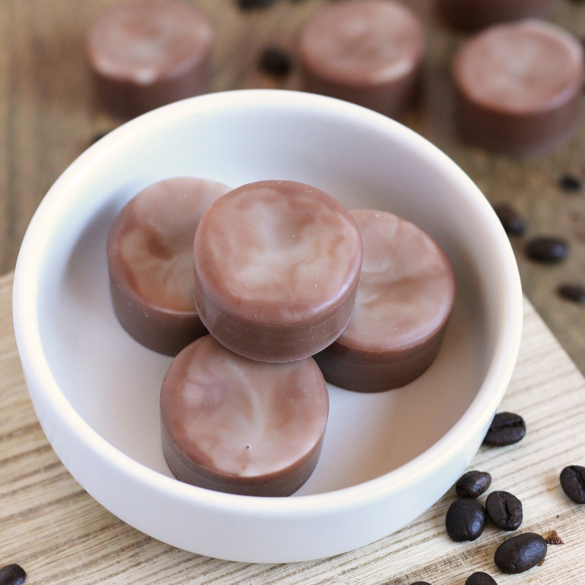 Brown and white swirled disk-shaped wax melts in a bowl on a wooden surface