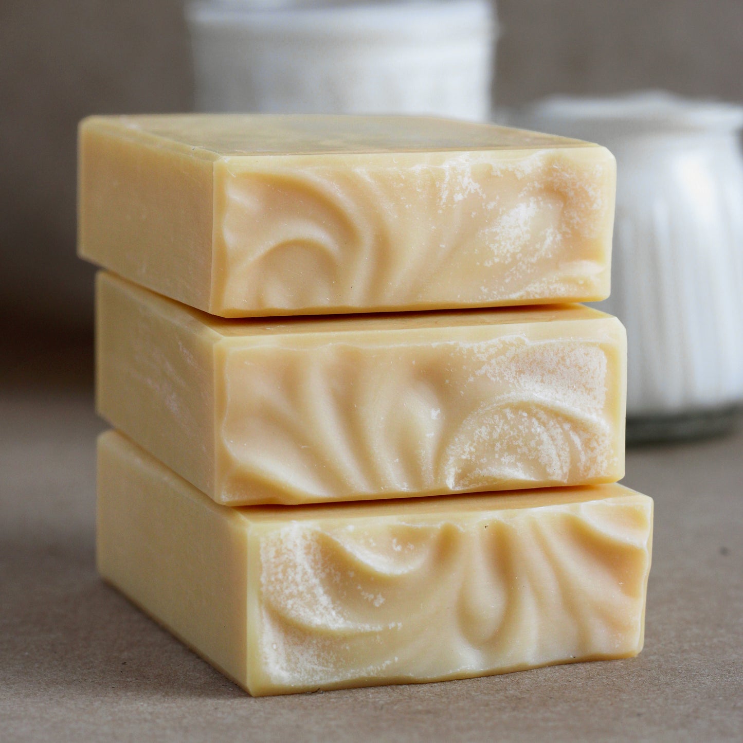 Missouri River Soap Lemongrass Tallow Soap featuring three creamy yellow handcrafted soap bars stacked on kraft paper with goat milk kefir and sheep's milk yogurt in the background.