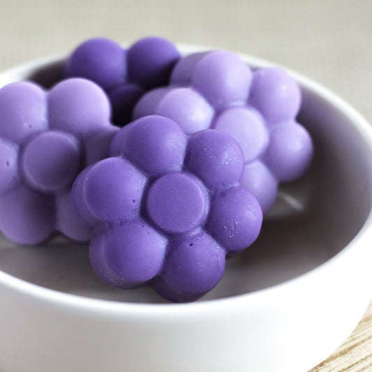 Various purple flower-shaped wax melts in a bowl