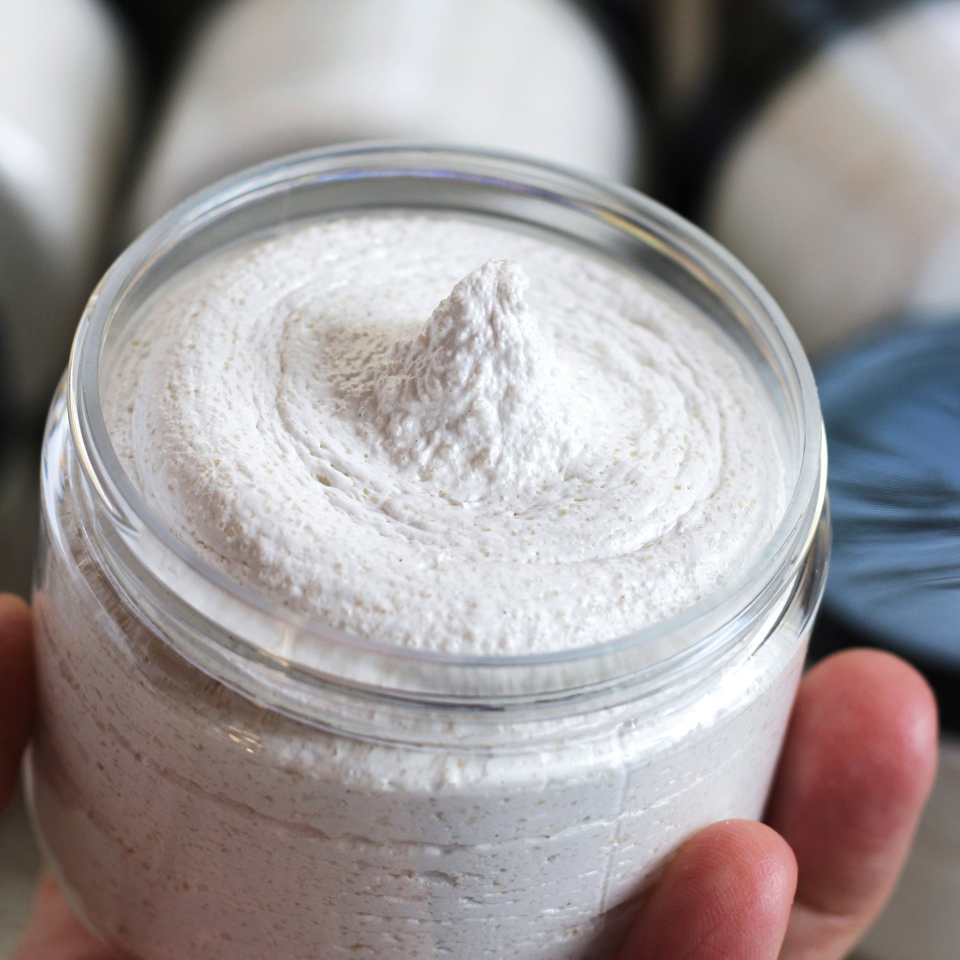 Jar of creamy scrub held in hand