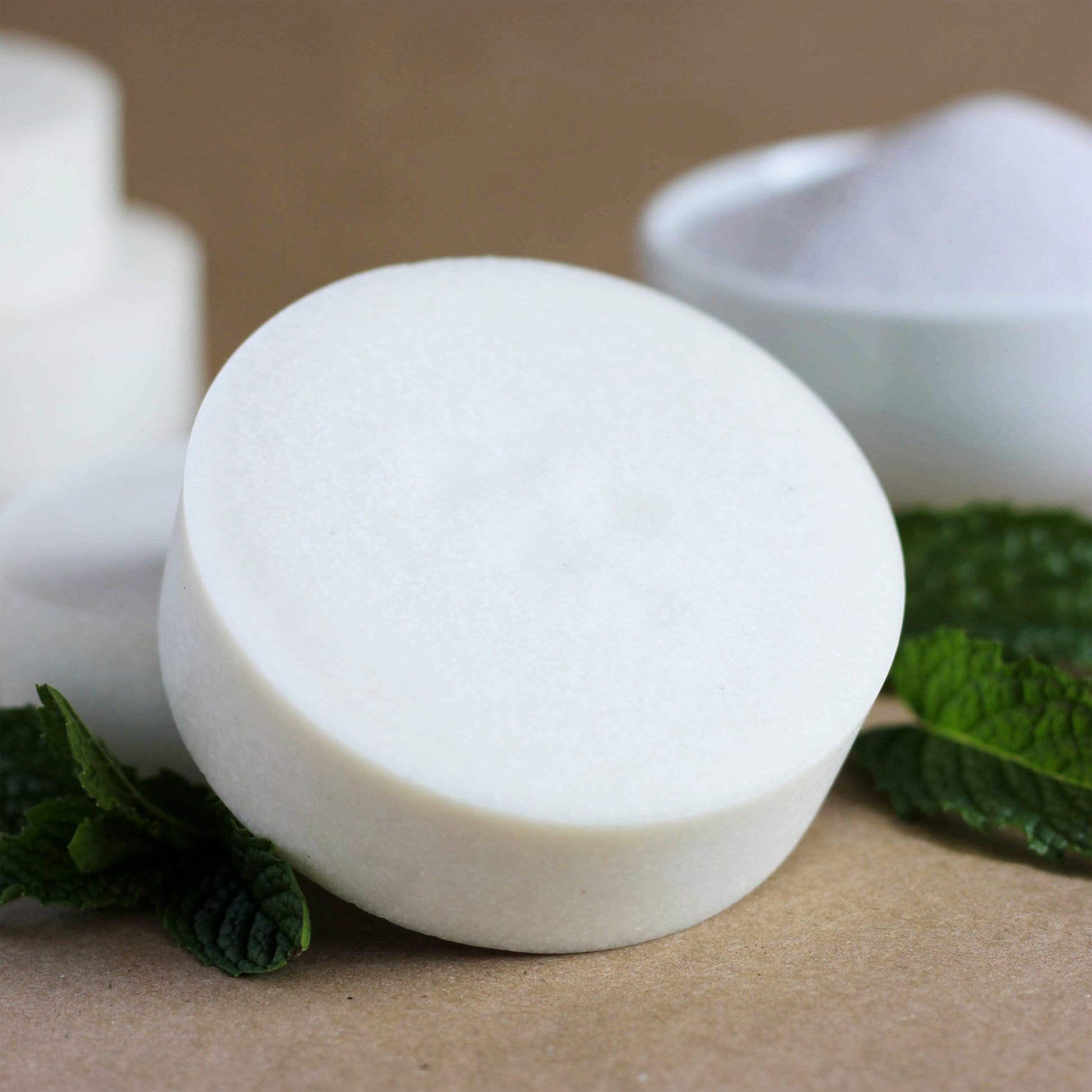 White soap bar with green leaves on a brown surface