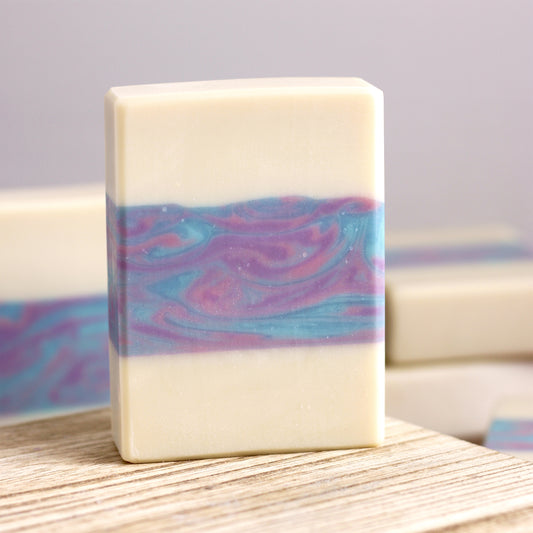 Cream colored soap with a swirled middle layer on a wood surface