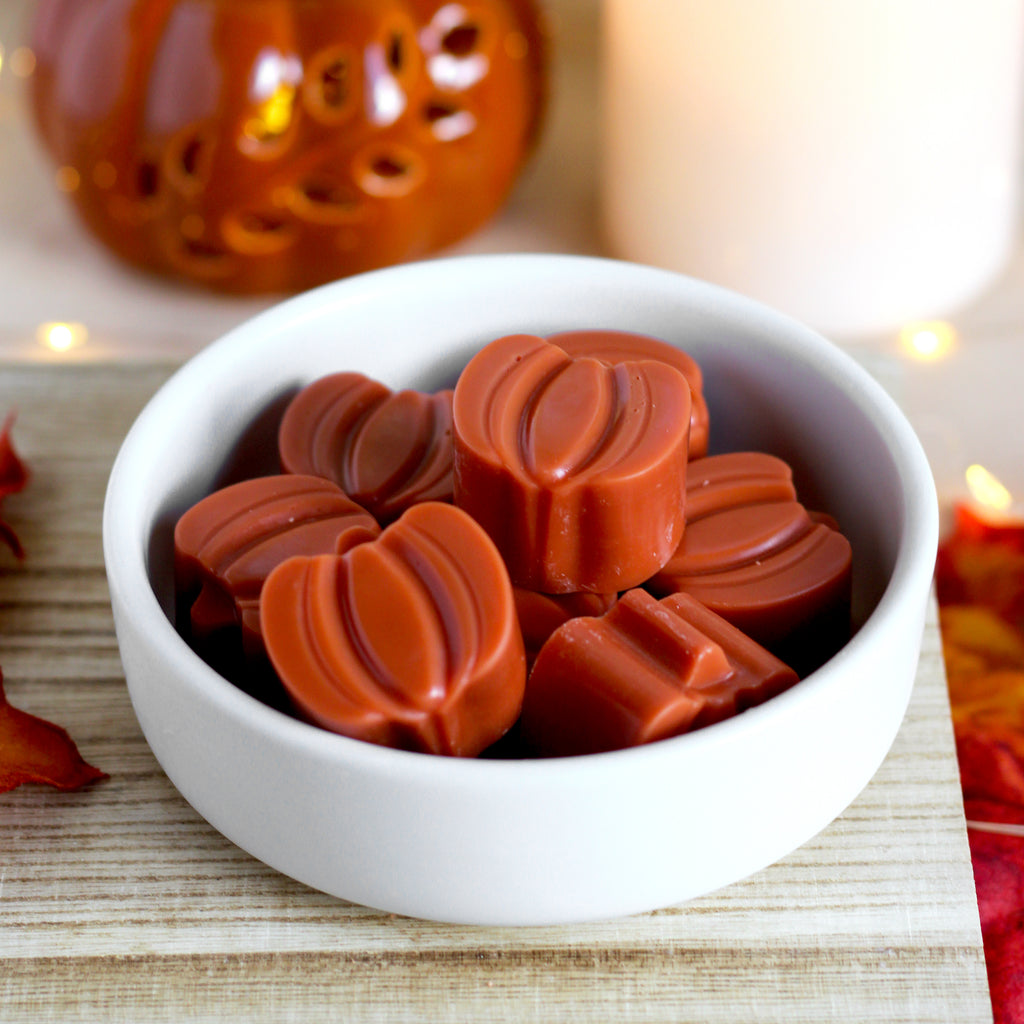 Pumpkin-shaped wax melts in a white bowl.