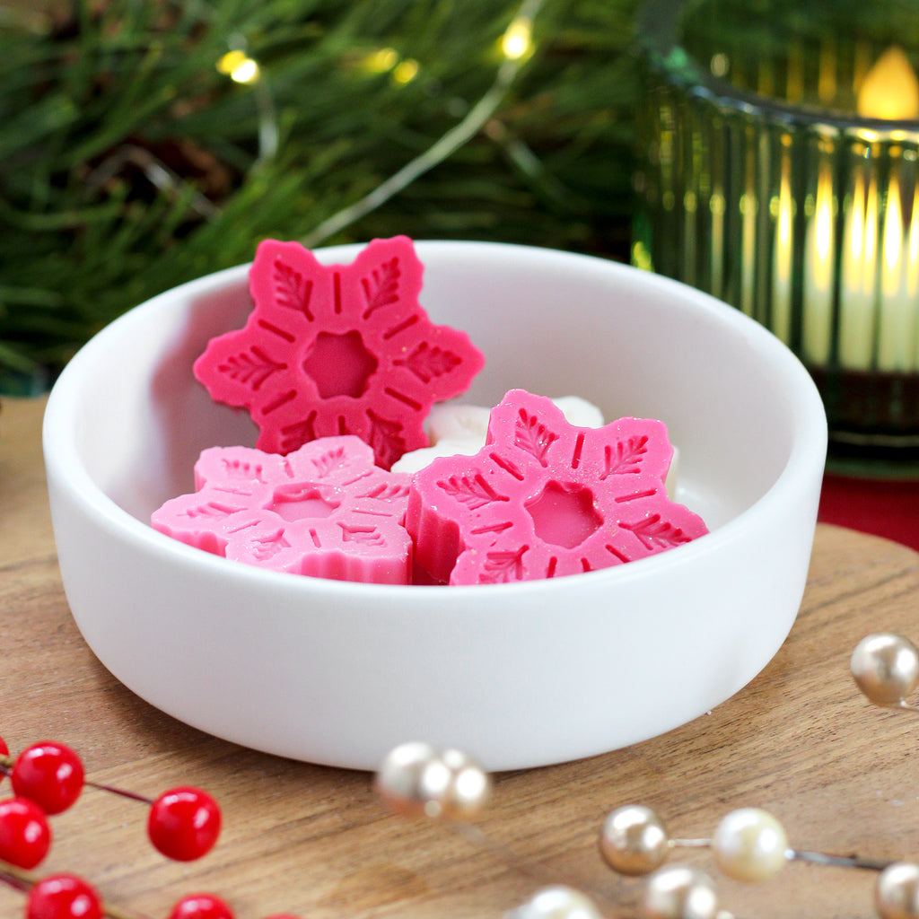Missouri River Soap Snow Kissed wax melts – four snowflake-shaped melts in white and pink, releasing a festive blend of candied apple, orange zest, earthy undertones, and a hint of warm spice