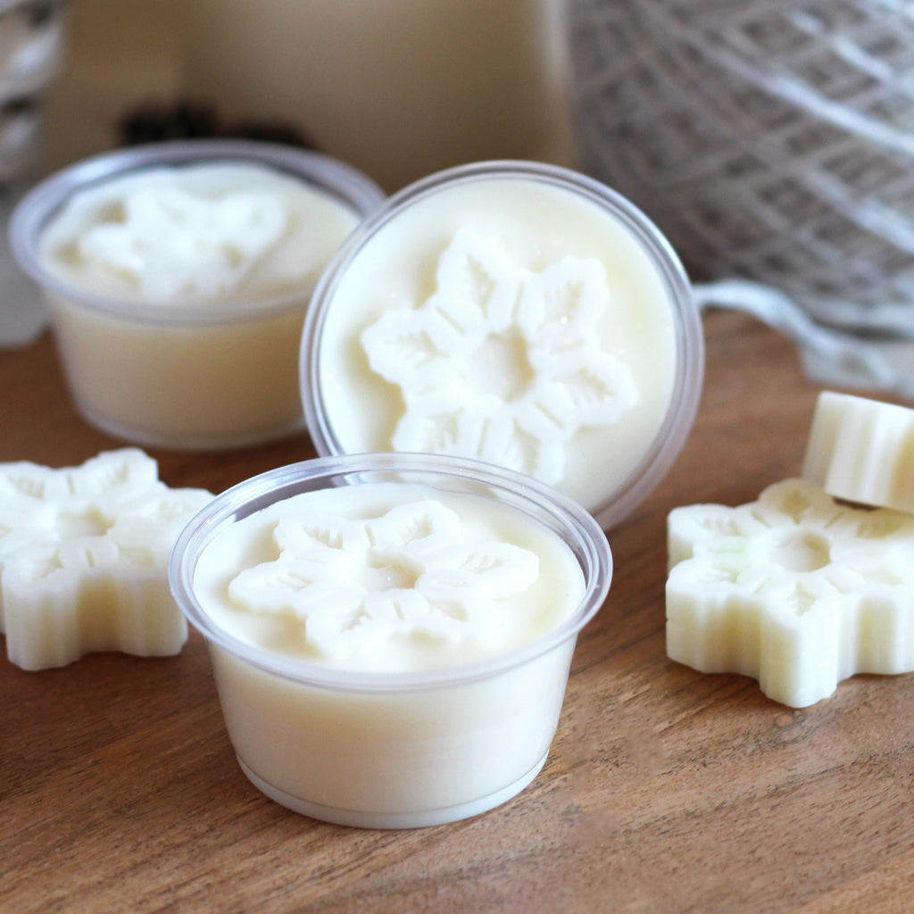 Creamy colored wax melt in a plastic cup with a snowflake shape on top