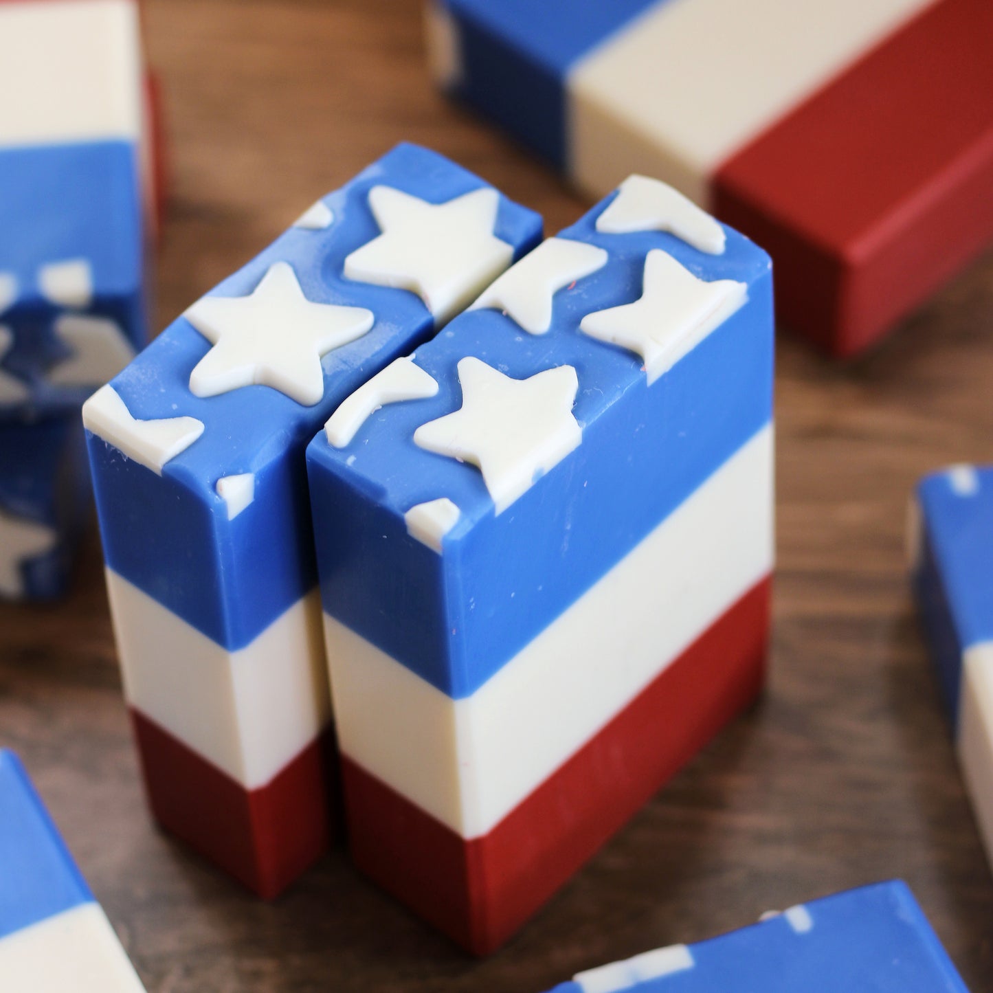 Handcrafted Stars & Stripes artisan soap with red, white, and blue layers, and white star embeds. Scented with black cherry, crisp apple, and sweet huckleberry. Made by Missouri River Soap