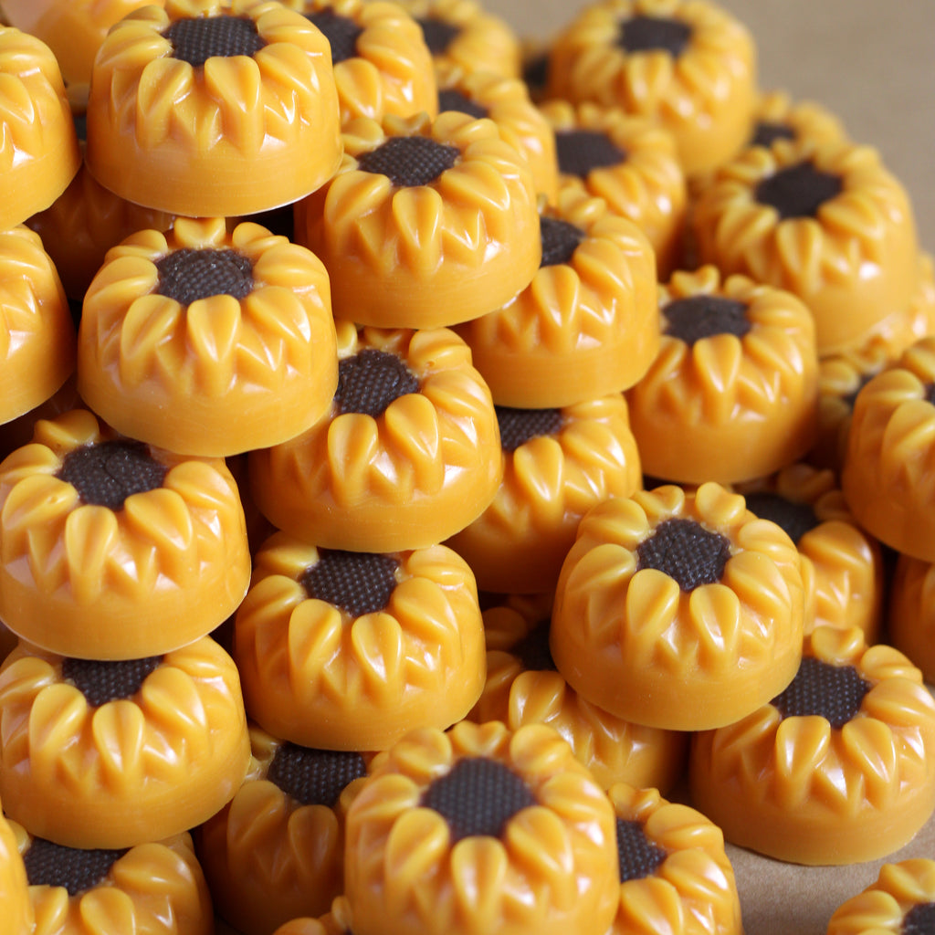 Stack of yellow sunflower-shaped wax melts with brown-black centers.