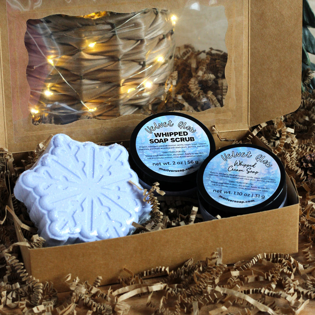Three Velvet Glow products in a box with string lights in the background.