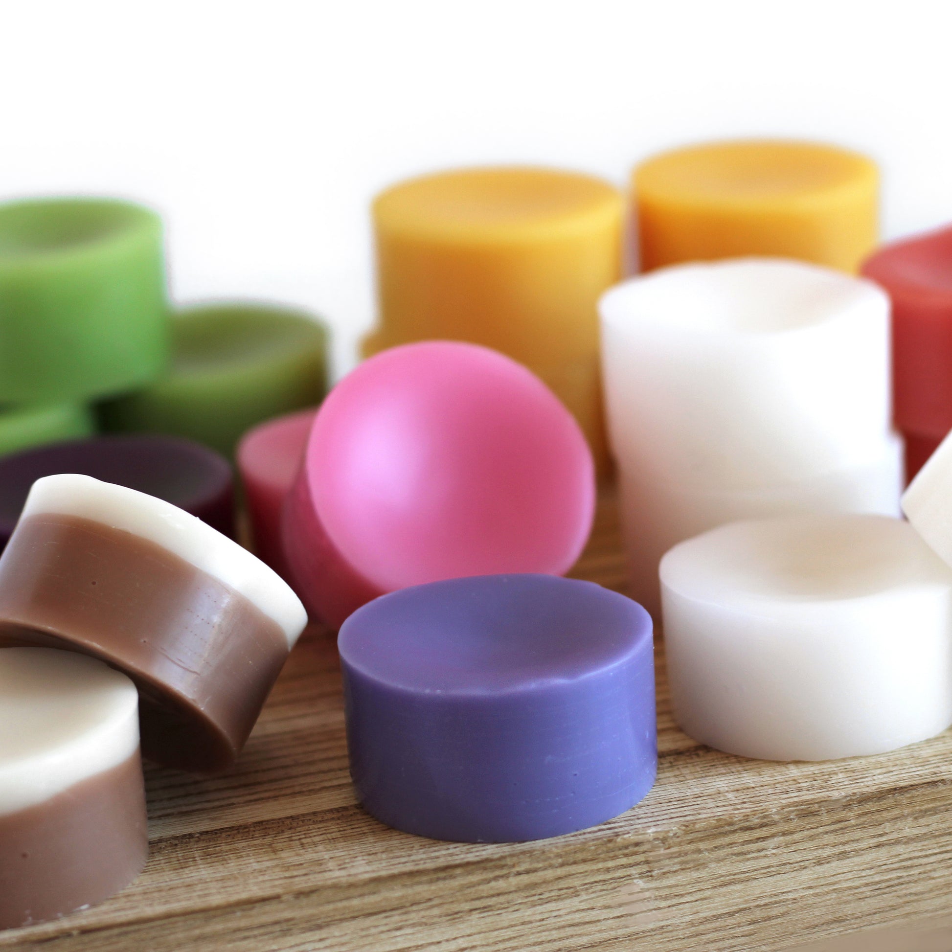 A variety of hand-poured scented wax melts in different colors, sizes, and made from soy and paraffin wax blends.