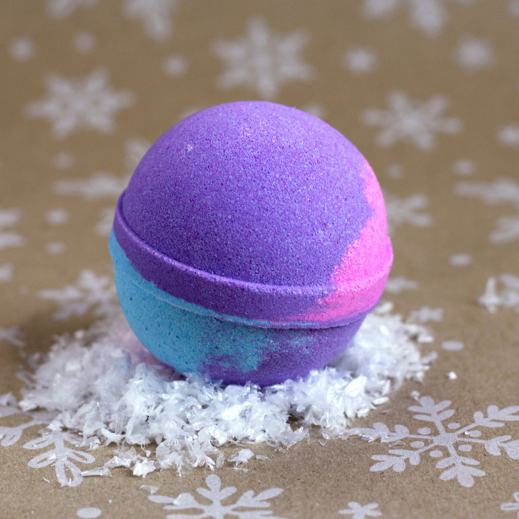 Wild Berry Blizzard bath bomb with swirls of purple, blue, and pink, on a snowflake-printed kraft background